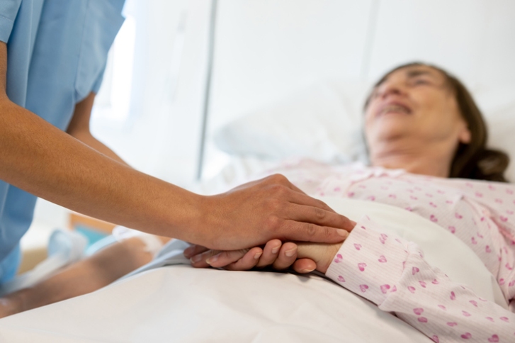 pielęgniarka trzyma za rękę leżącą kobietę